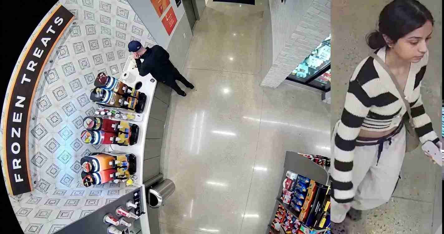 Surveillance-style store scene: a man browses beverages at a curved display while a woman in a striped cardigan walks by on the right.