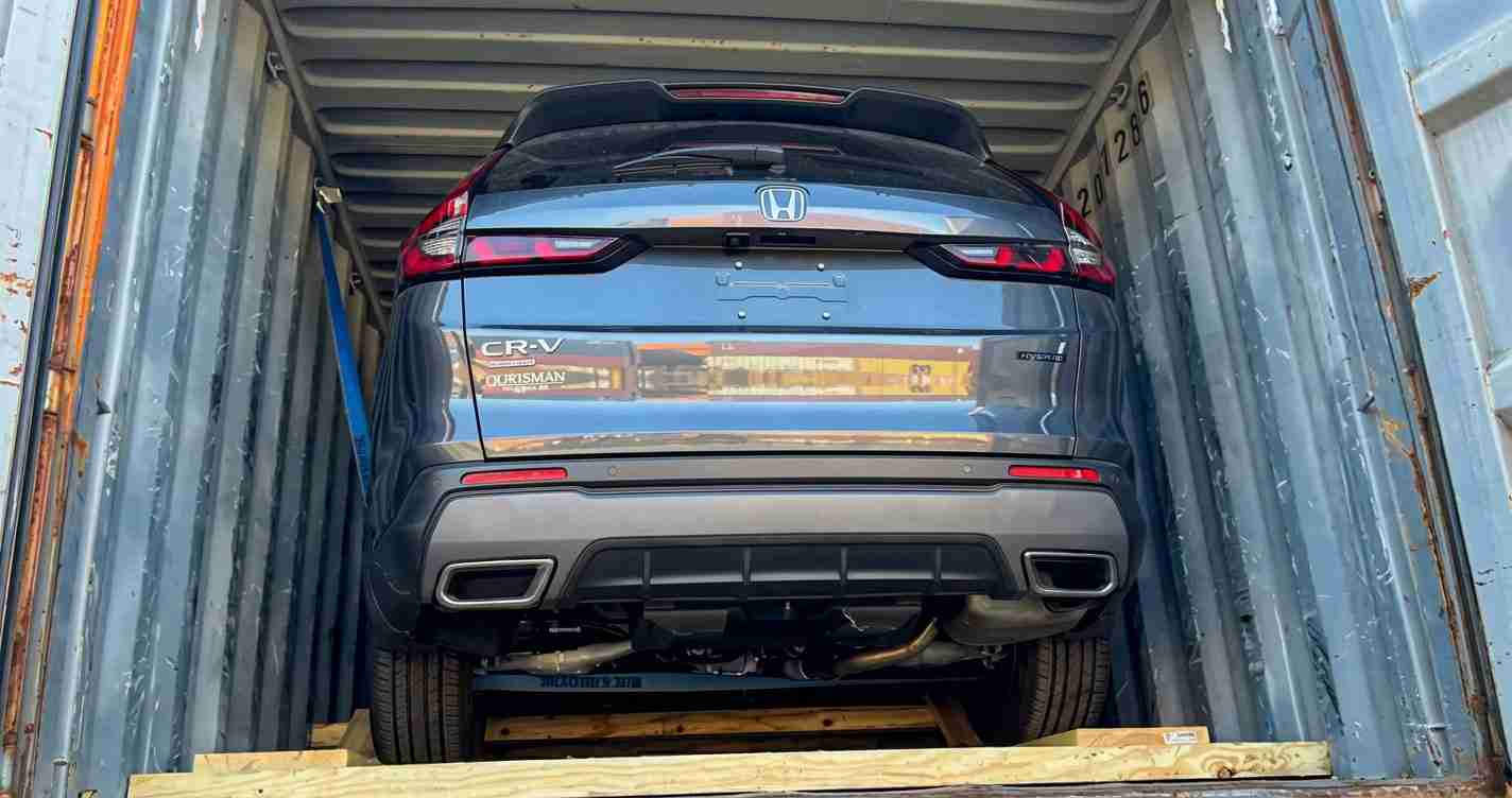 Blue Honda CR-V seen from the rear, inside a metal shipping container on a wooden pallet frame