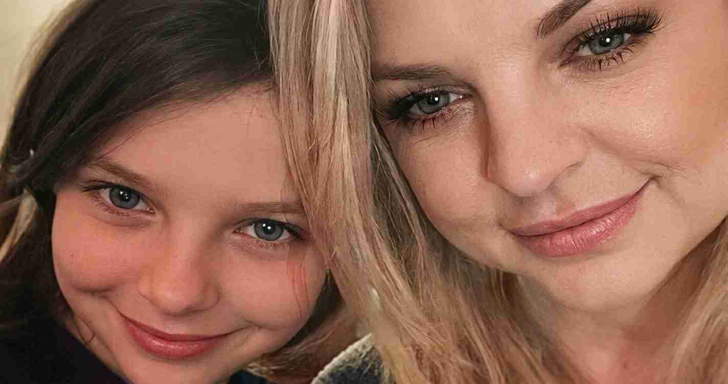 Smiling mother and daughter posing for a close-up selfie.