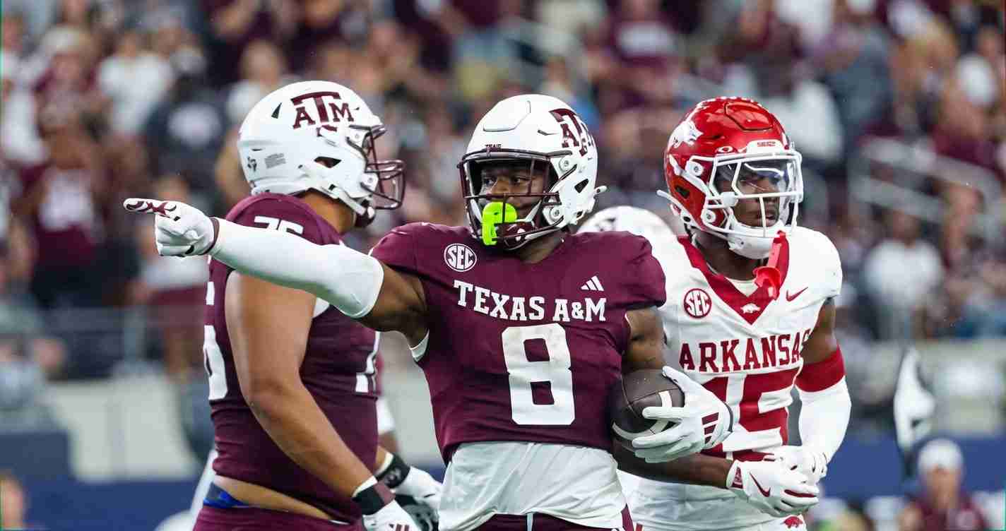 Texas A&M player (No. 8) carries the ball as an Arkansas defender closes in during a college football game against Arkansas.