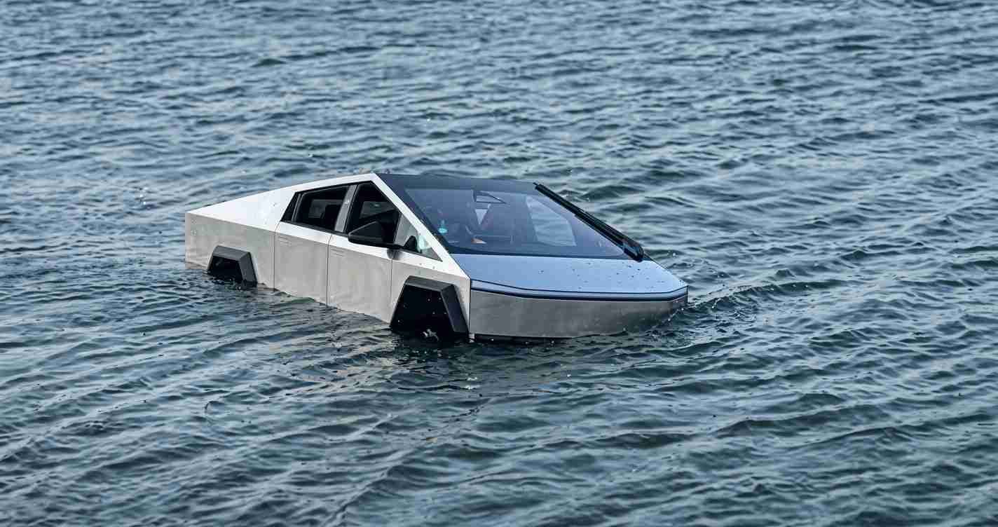 Silver angular car partially submerged in rough ocean water, with visible windshield wipers.