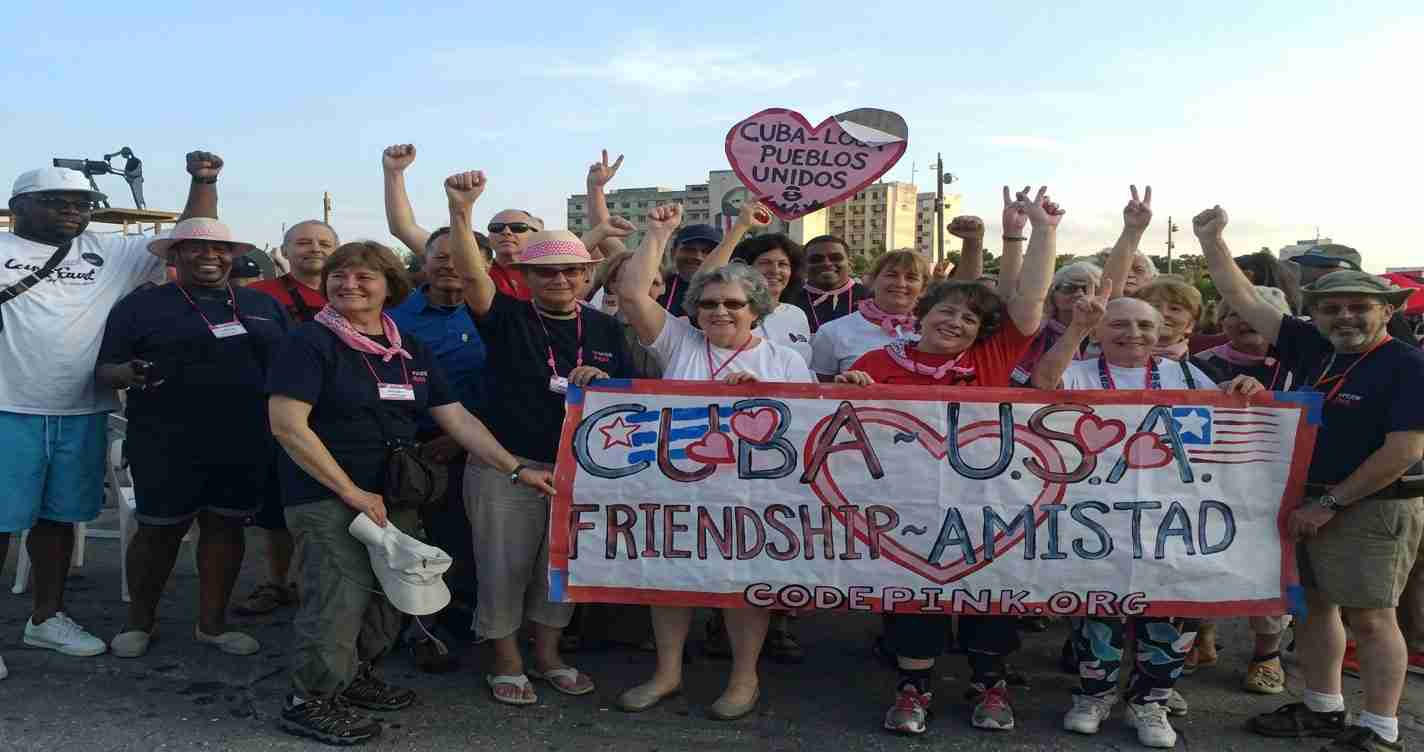 Group photo of diverse people at a Cuba–USA friendship rally, holding a banner reading 'CUBA USA FRIENDSHIP AMISTAD'.