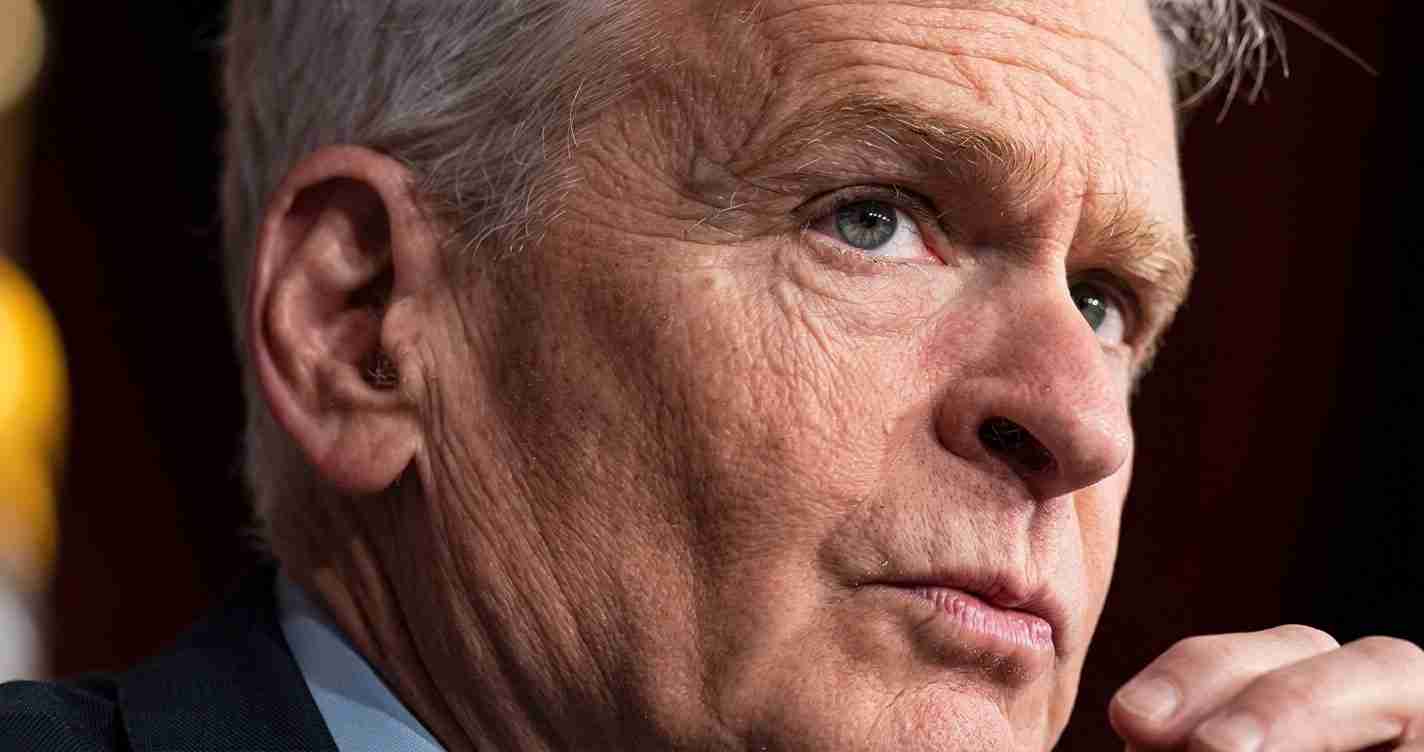 Close-up of an older man with gray hair, looking to the right with a thoughtful expression.