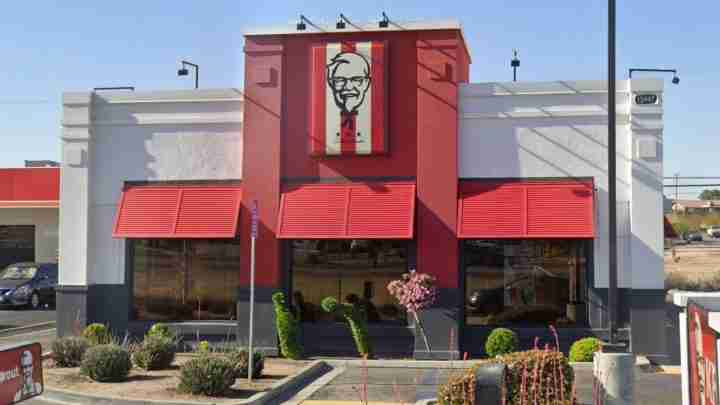 Exterior of a KFC restaurant with red facade, red awnings, and the Colonel Sanders logo above the entrance.