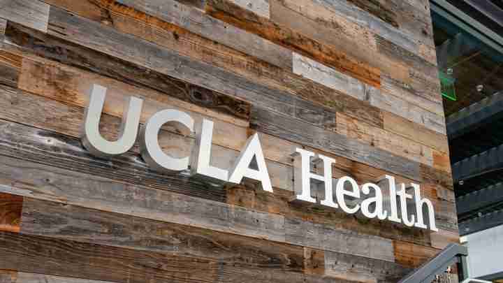 Wooden plank wall with white 'UCLA Health' sign mounted outside a building.